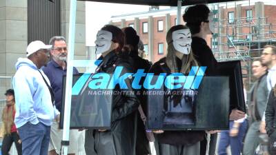  Aktivisten mit Guy-Fawkes-Masken stehen regungslos, Rücken an Rücke - Rechtswidrige Verstöße gegen Tierschutzgesetze - Außergewöhnliche Misshandlungen gegen Tiere - Sie verlangen Gerechtigkeit für Tiere